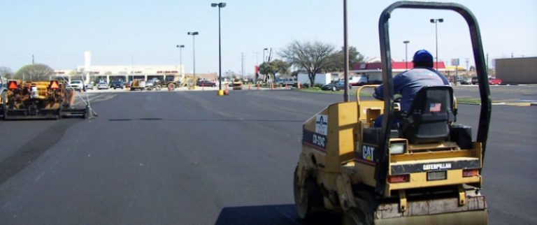 Fresh asphalt being laid over existing road surface as part of asphalt overlay service