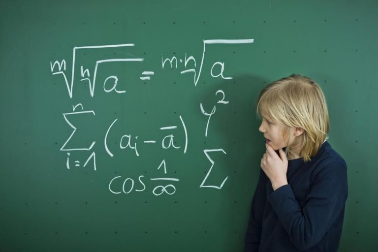 A teacher helping students with math problems at desks in a bright classroom