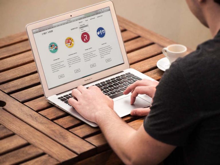 A person working on a MacBook, focused on the screen in a modern workspace.