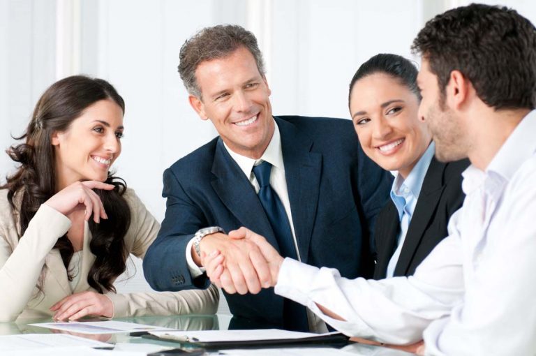 Two professionals shaking hands in a business setting, representing partnership and agreement.