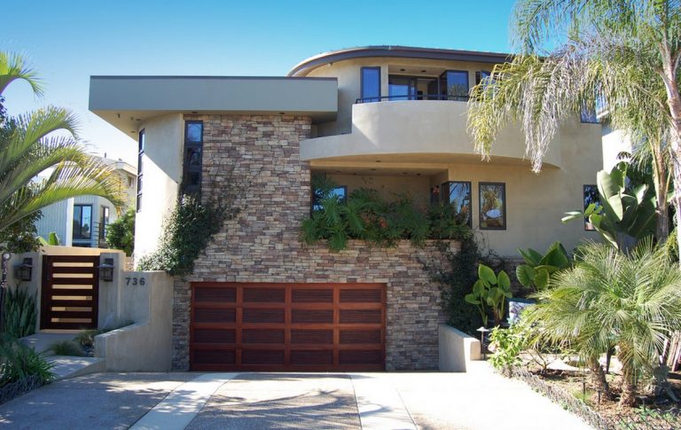 A contemporary garage door with wood and glass panels on a home exterior