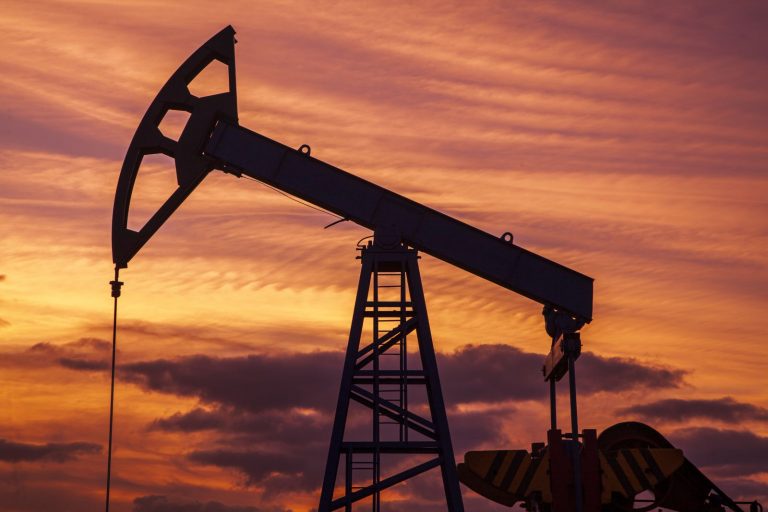 Close-up of an oil rig with industrial pipes and machinery under a blue sky
