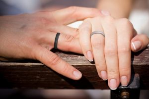 Close-up of couple’s hands wearing matching tungsten wedding rings on ring fingers